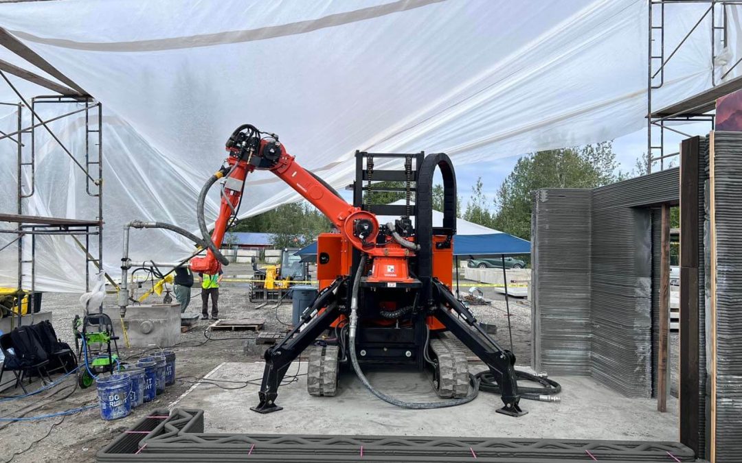 On orange 3D printer sits atop a partially printed concrete foundation.
